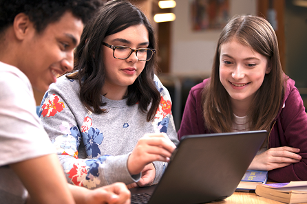 Tres alumnes treballant davant un ordinador portàtil