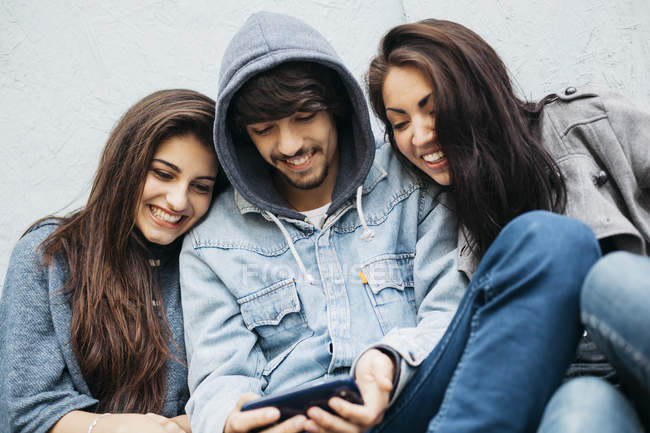 Imatge tres persones compartint un dispòsitiu mòbil