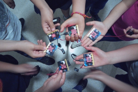 Mans de joves amb plaques de Micro:bit en un curs impartit per Colectic
