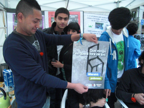 Joves de l'Òmnia Teb amb cartell de la Marató per la Pobresa